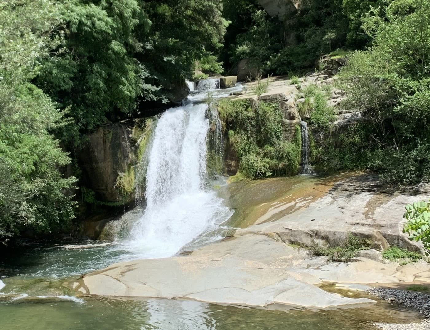A waterfall falling into a green pool over pale rock