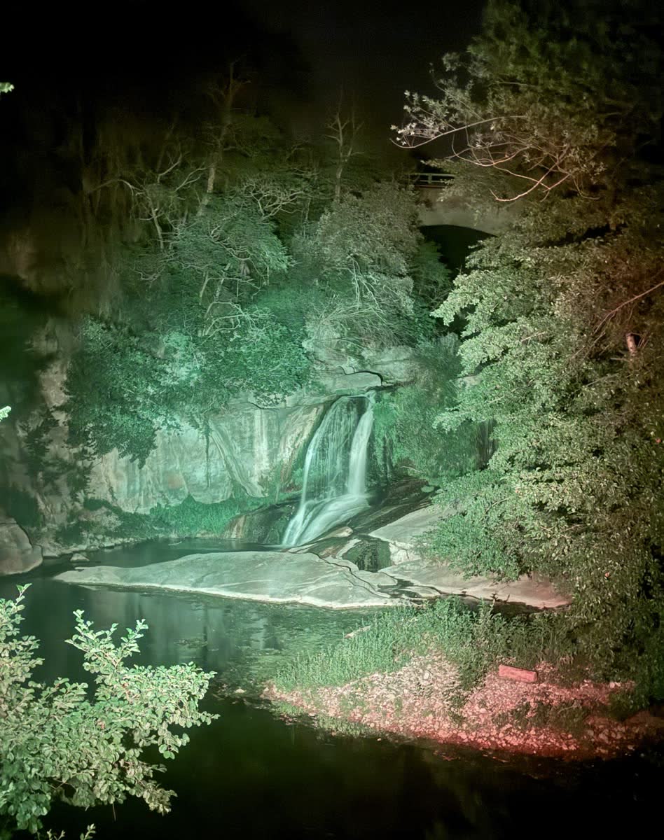 The same waterfall lit green at night